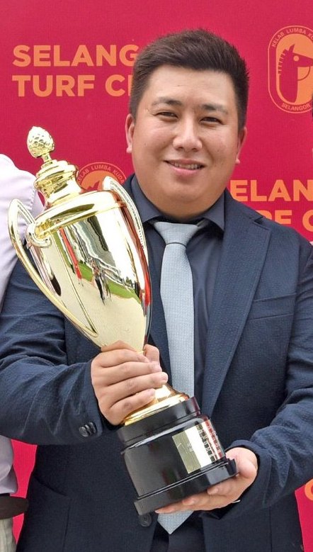 Trainer HY Cheng holding a trophy